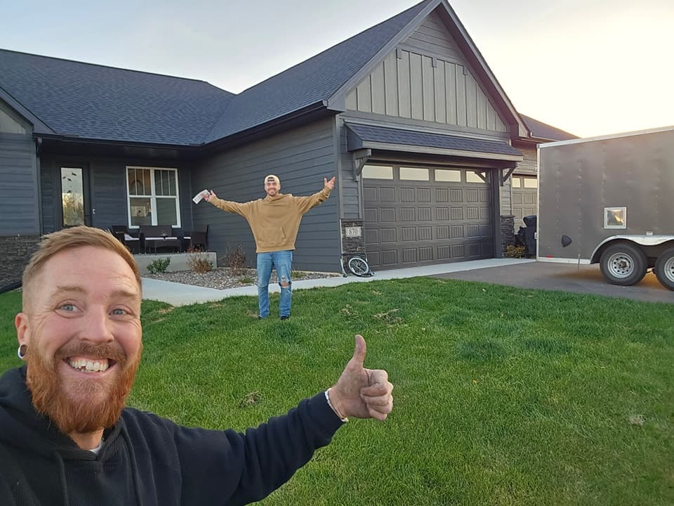 Happy customer with arms outstretched in front of a finished home